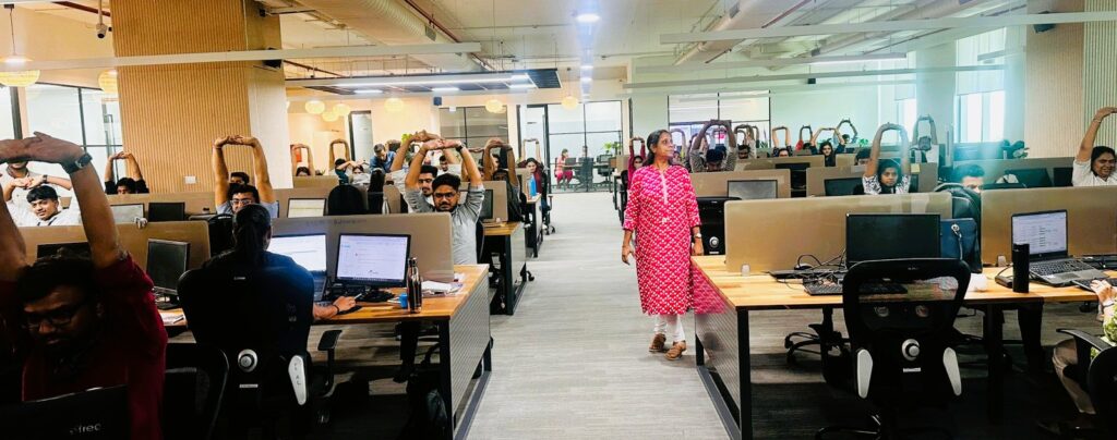 Corporate employees performing guided yoga stretches during Asmakam Gram’s workplace wellness session.