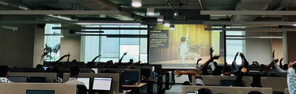 Employees participating in Asmakam Gram’s corporate yoga session to promote workplace wellness and mindful movement.